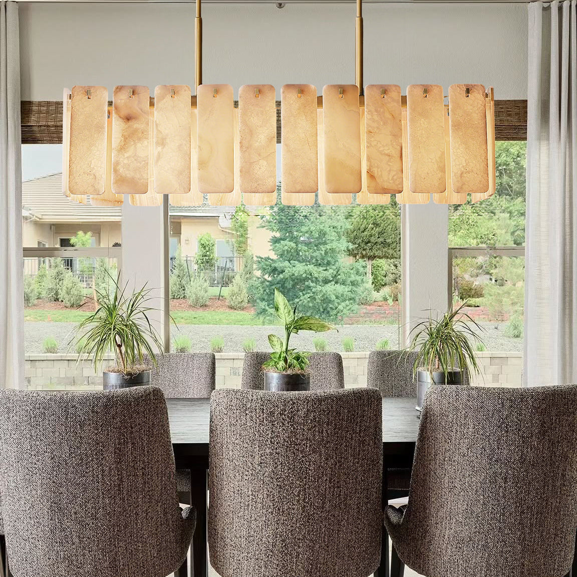 Dining room with a long wooden table and chairs, featuring a modern pendant light.